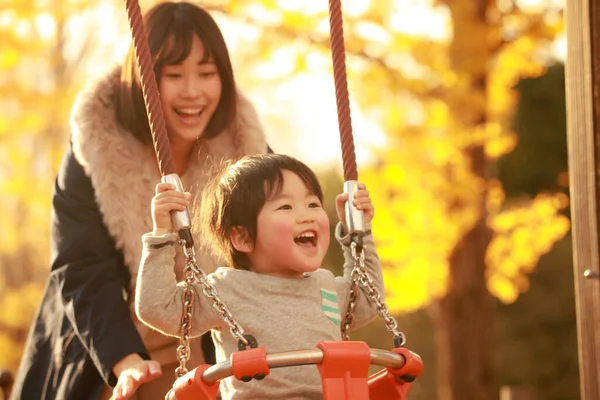 Küçük sevimli Asyalı çocuk ve annesi parkta.