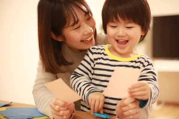 Gülümseyen Asyalı genç kadın ve küçük oğlu el kreması yapıyorlar. 