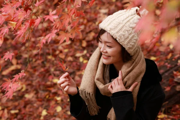 Sonbahar parkında poz veren Asyalı genç kadının portresi. 