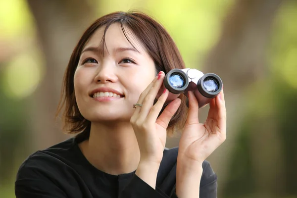 公园里拿着双筒望远镜的年轻亚洲女人的肖像 — 图库照片