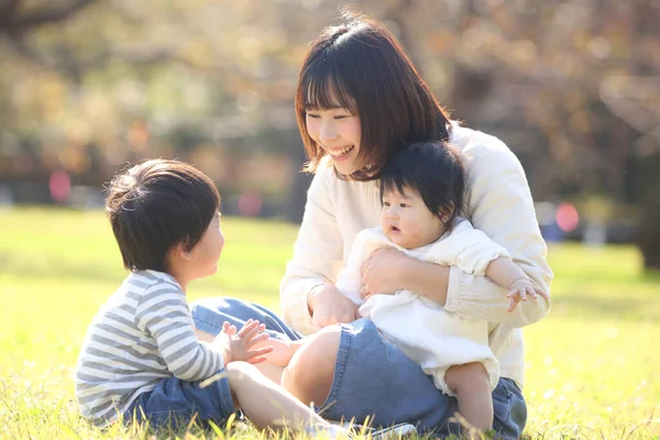 公園で母親と一緒に暮らすアジア系の子供たちは — ストック写真