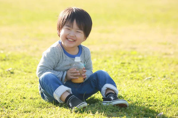 Parkta meyve suyu içen mutlu çocuk portresi