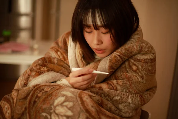 Asyalı kadın vücut ısısını dijital termometreyle kontrol ediyor