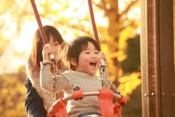 Küçük sevimli Asyalı çocuk ve annesi parkta.