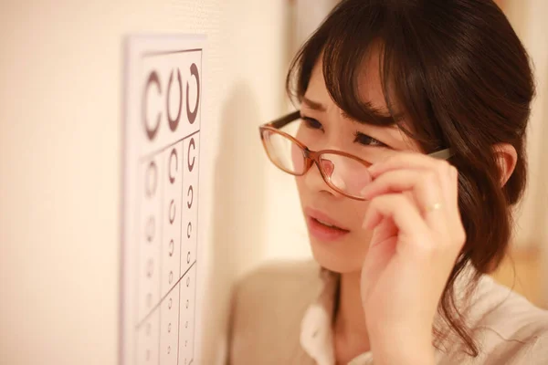 メガネと目の検査表を持つ若いアジアの女性 — ストック写真