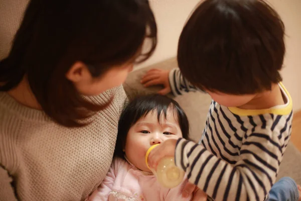 Mały Japończyk Pomaga Matce Karmić Młodszą Siostrę Mlekiem — Zdjęcie stockowe