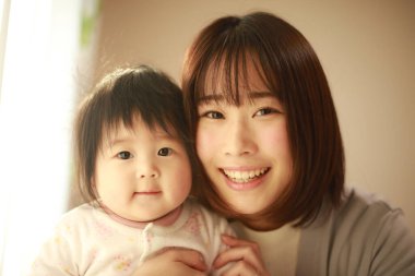 Gülümseyen Asyalı genç kadın ve küçük kızı 