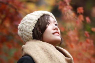 Sonbahar parkında poz veren Asyalı genç kadının portresi. 