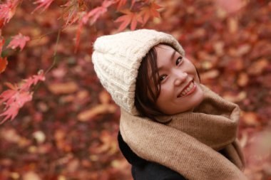 Sonbahar parkında poz veren Asyalı genç kadının portresi. 