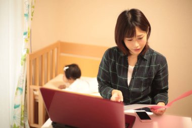 Kadın çocuğuyla birlikte evden çalışıyor.