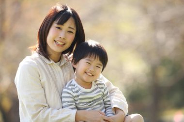 Asyalı anne oğluna sarılıyor.