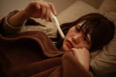 Termometresi olan genç Asyalı kadın hasta. 