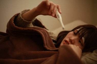 Termometresi olan genç Asyalı kadın hasta. 