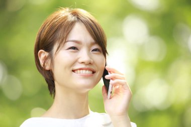 Genç Asyalı kadın cep telefonuyla konuşuyor.