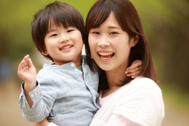 Genç Asyalı anne ve küçük oğlu parkta eğleniyorlar.  