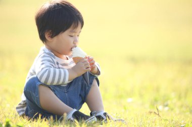 Çocuk parkta dondurma yiyor. 