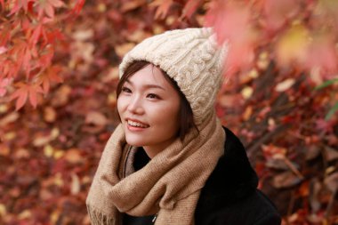 Sonbahar parkında poz veren Asyalı genç kadının portresi. 