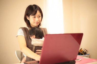 Kadın çocuğuyla birlikte evden çalışıyor.