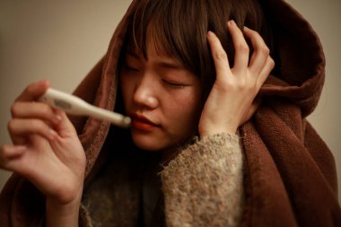 Termometresi olan genç Asyalı kadın hasta. 