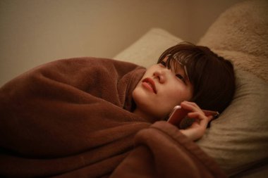 Yatakta yatarken ve smartphone kullanarak kadın