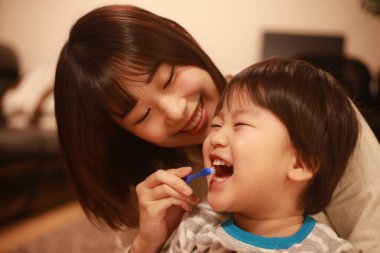 Genç anne, küçük oğlu için dişlerini fırçalıyor.