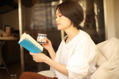 Kanepede kitap okuyan güzel bir kadın.