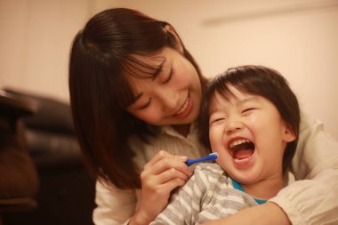 Genç anne, küçük oğlu için dişlerini fırçalıyor.