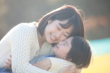 Küçük sevimli Asyalı çocuk ve annesi parkta.