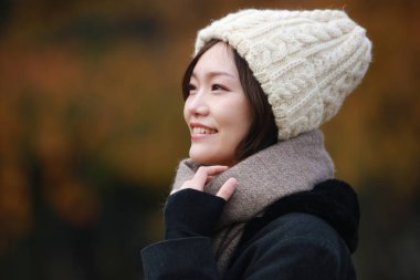 Sonbahar parkında poz veren Asyalı genç kadının portresi. 