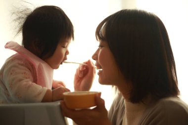 Genç anne, sevimli bebeği evde besliyor.