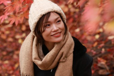 Sonbahar parkında poz veren Asyalı genç kadının portresi. 