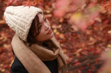 Sonbahar parkında poz veren Asyalı genç kadının portresi. 