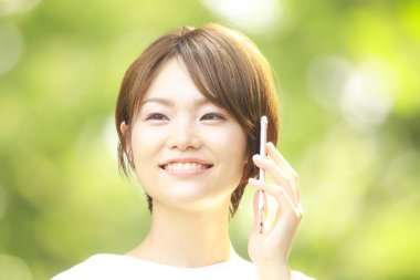 Genç Asyalı kadın cep telefonuyla konuşuyor.