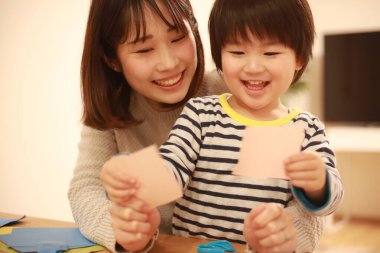 Gülümseyen Asyalı genç kadın ve küçük oğlu el kreması yapıyorlar. 