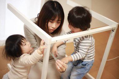 Çocuklu Asyalı kadın yeni evinde masa topluyor.