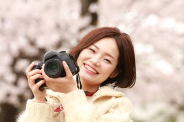 Parkta kamerası olan genç bir kadın.