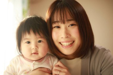 Gülümseyen Asyalı genç kadın ve küçük kızı 