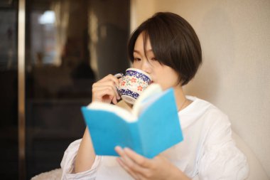 Kanepede kitap okuyan güzel bir kadın.