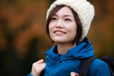 Sonbahar parkında poz veren Asyalı genç kadının portresi. 