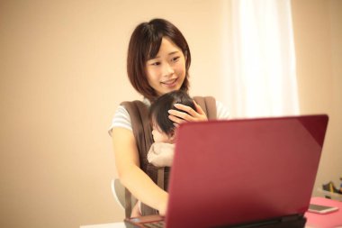 Kadın çocuğuyla birlikte evden çalışıyor.