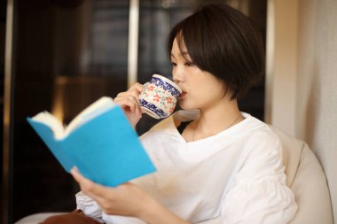 Kanepede kitap okuyan güzel bir kadın.