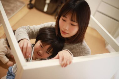 Küçük oğlu olan Asyalı kadın yeni evinde toplanıyor.