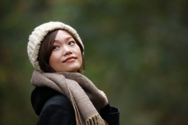 Sonbahar parkında poz veren Asyalı genç kadının portresi. 