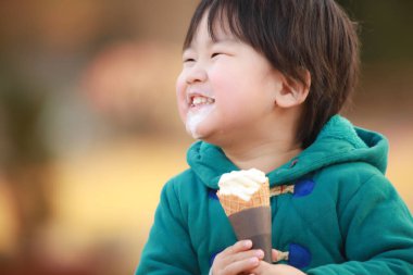 Çocuk parkta dondurma yiyor.