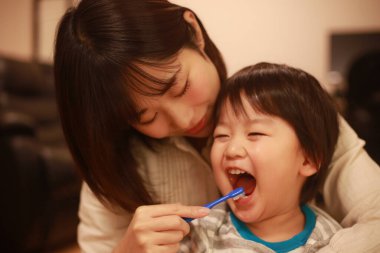 Genç anne, küçük oğlu için dişlerini fırçalıyor.