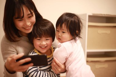 Mutlu Asyalı aile televizyon izlemek için cep telefonu kullanıyor.