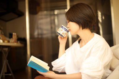 Kanepede kitap okuyan güzel bir kadın.