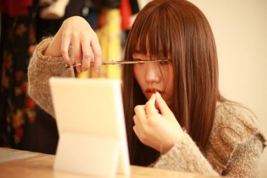 Güzel Asyalı kadın saçını kesiyor. 