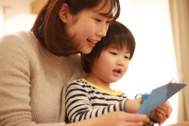 Gülümseyen Asyalı genç kadın ve küçük oğlu el kreması yapıyorlar. 