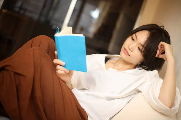 ソファーに横になって本を読む美しい女性 — ストック写真